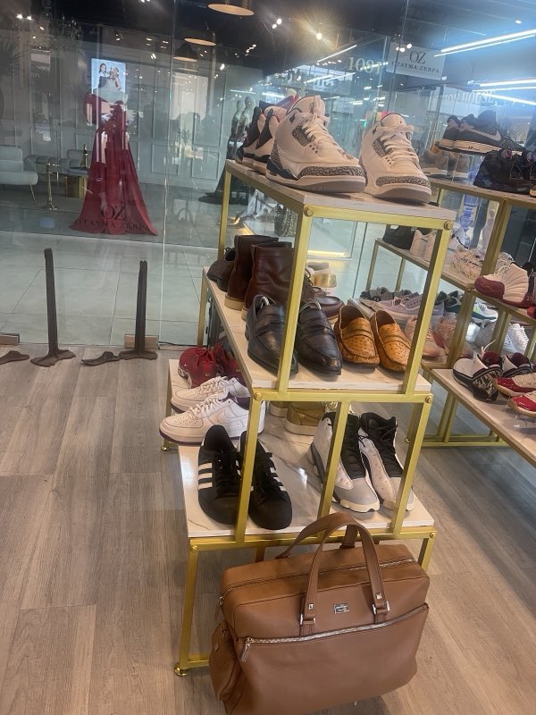 Restored sneakers and a leather duffel arranged on gold shelving